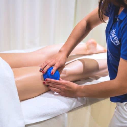 Terapetka spa wykonująca masaż bańką chińską na lewej nodze klientki
