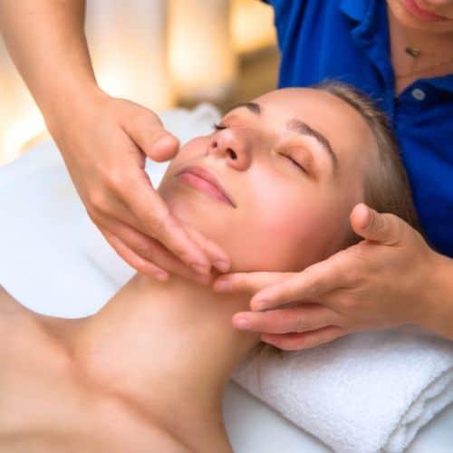 Terapeutka spa wykonująca specjalistyczne ruchy masażu kobido na twarzy klientki